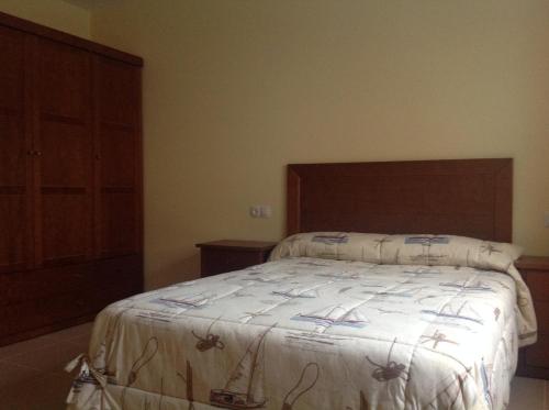 a bedroom with a large bed with a wooden headboard at Casa As Pedreiras in Barreiros