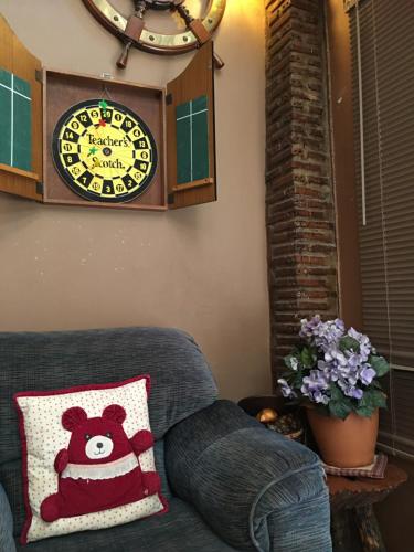 a clock on the wall above a couch with a pillow at The Green land (Khok Kruat) in Nakhon Ratchasima