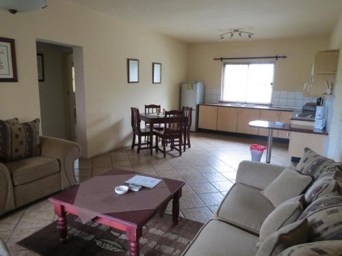 a living room with a couch and a table and a kitchen at Crocodile Lodge cc in Midrand