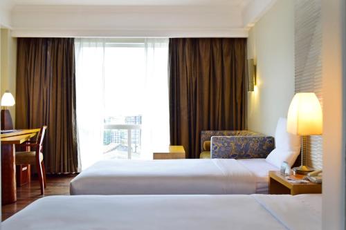 a hotel room with two beds and a desk at Novotel Semarang in Semarang
