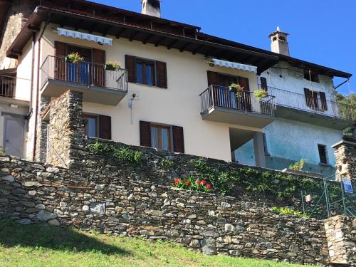 Cette maison ancienne est dotée de fenêtres et d'un mur en pierre. dans l'établissement Lake Como Panoramic View, à Domaso