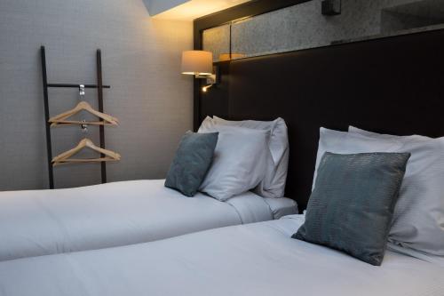 two beds in a hotel room with white sheets and pillows at Camden Enterprise Hotel in London