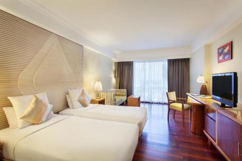 a hotel room with two beds and a flat screen tv at Novotel Semarang in Semarang