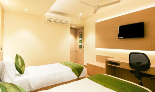 a hotel room with a bed and a desk and a tv at Treebo Hoops - Airport, VIP Road in Kolkata