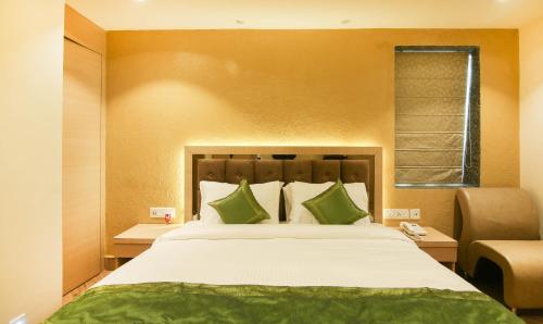 a bedroom with a large bed with green pillows at Treebo Hoops - Airport, VIP Road in Kolkata