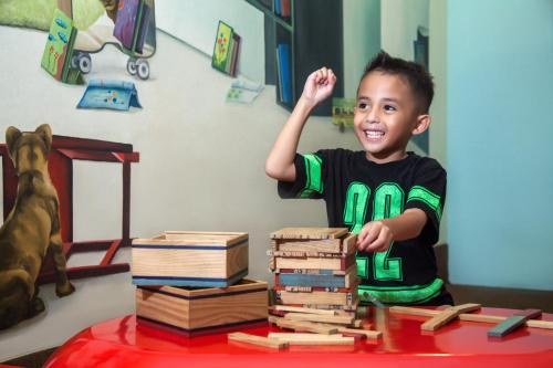 a young boy standing next to a pile of books at Novotel Semarang in Semarang