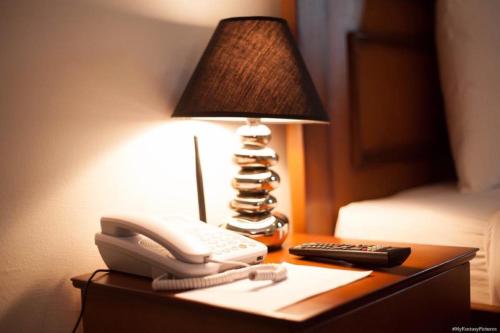 um telefone e um candeeiro numa mesa com uma cama em Hotel Adagio em Libreville