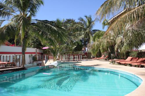 une grande piscine bordée de palmiers et de chaises dans l'établissement Les Flamboyants, à Saly Portudal