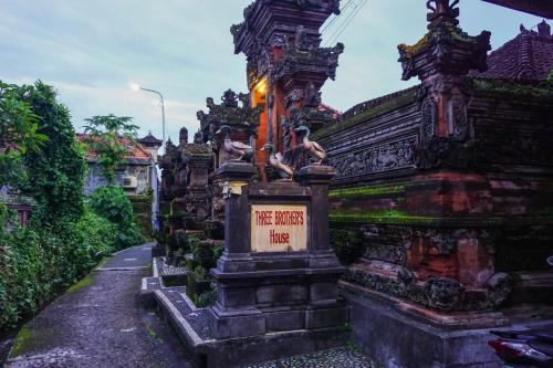 a building with a sign on the side of a street at Three Brothers Guest House in Ubud
