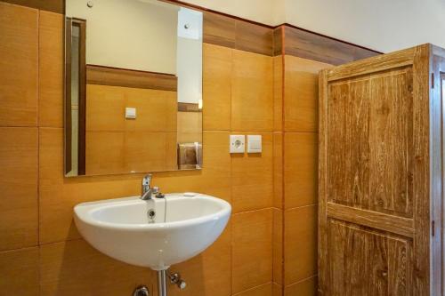 een badkamer met een wastafel en een houten deur bij Three Brothers Guest House in Ubud
