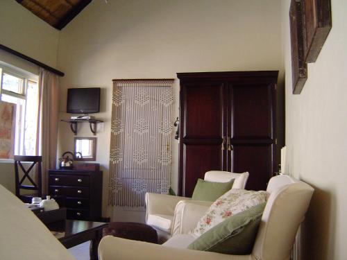 een woonkamer met een bank en stoelen en een televisie bij Forest Creek Lodge & Spa in Badfontein