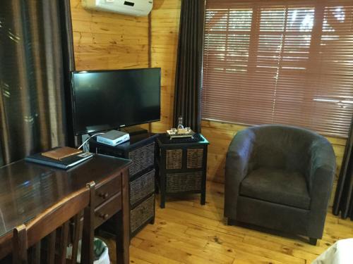 een woonkamer met een stoel en een televisie bij Sanyati Guesthouse in Kathu