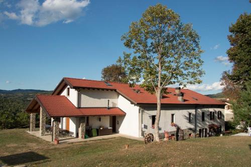 a white house with a red roof and a tree at Il Casolare Bioenergetico in Albareto