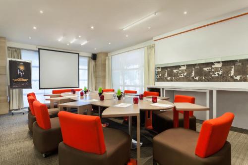 a conference room with tables and chairs and a screen at Novotel Semarang in Semarang