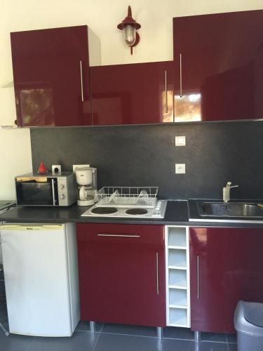 a kitchen with red cabinets and a stove and a sink at CAVALIERE STUDIO 2P TER in Le Lavandou