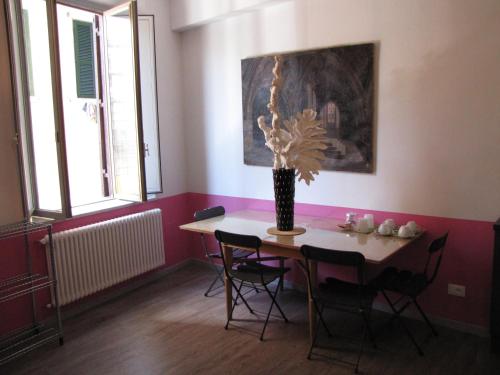 una sala da pranzo con tavolo, sedie e vaso con fiori di Trastevere Colors a Roma