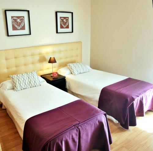 a hotel room with two beds and a couch at Aparthotel Encasa in Madrid