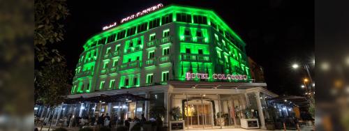 a green building with people standing in front of it at Hotel Colosseo Tirana in Tirana