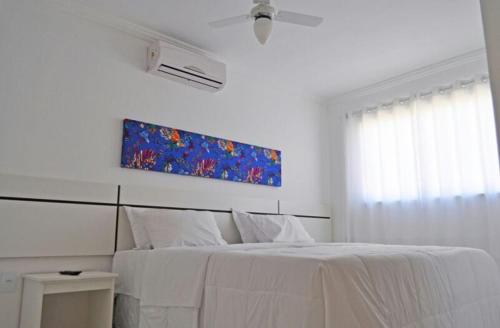 um quarto branco com uma cama e um quadro na parede em apartamento monte hebron em Porto Seguro