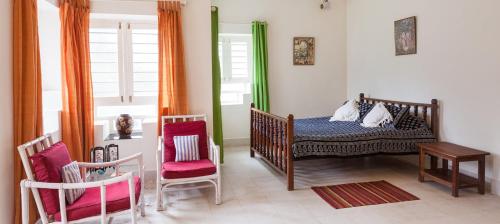 a bedroom with a crib and two chairs and a table at Coorg Kolamotte in Gonikoppal