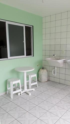 baño con mesa, 2 taburetes y lavamanos en Pousada Mar Verde, en Florianópolis