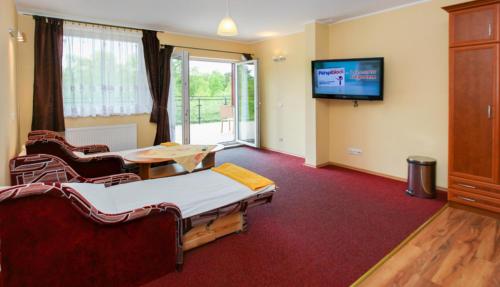 ヤストシェンビャ・グラにあるOkulski Grand Rozewieのベッド2台、テーブル、テレビが備わる客室です。