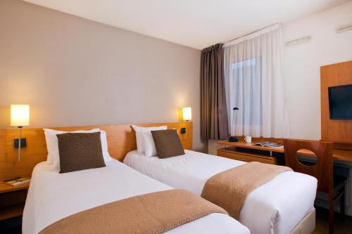 a hotel room with two beds and a desk at Séjours & Affaires Pantin Charles De Gaulle in Pantin