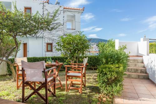 um pátio com cadeiras e uma mesa em frente a uma casa em Maistros Suites - Péra em Skopelos Town