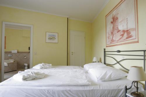 a bedroom with two white beds and a bathroom at Hotel Landhaus Milser in Duisburg
