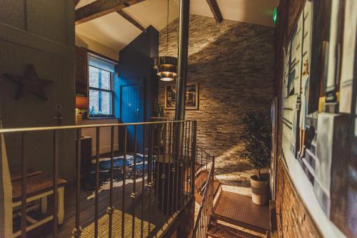 a hallway with a staircase and a brick wall at The Cow Hollow Hotel in Manchester