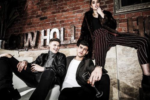 a group of three people sitting next to a brick wall at The Cow Hollow Hotel in Manchester