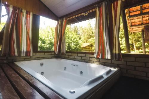 a large bath tub in a room with windows at Hotel Vale das Hortênsias in Joinville