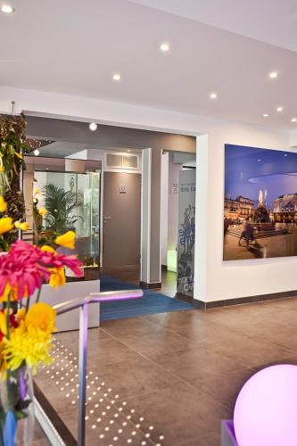 a lobby of a building with a large painting on the wall at Privilège Hôtel & Apparts Eurociel Centre Comédie in Montpellier