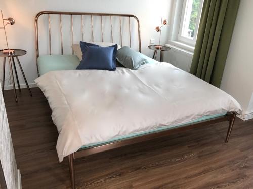 a bed with white sheets and blue pillows on it at Quartier 1903 in Oldenburg