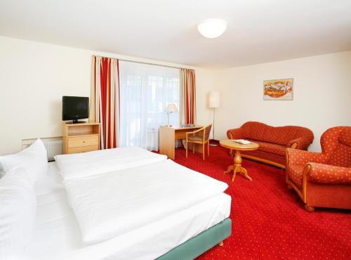 ミュンヘンにあるホテル ビーダーシュタイン アム エングリッシェン ガルテンの白いベッドとソファが備わるホテルルームです。
