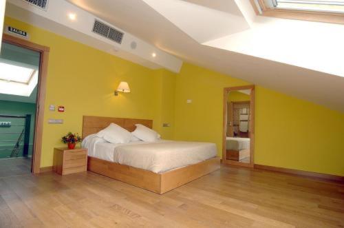 a bedroom with a bed and a yellow wall at Hotel O Desvio in Santiago de Compostela