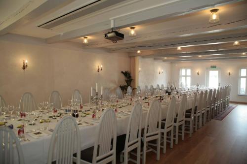 a large banquet hall with white tables and white chairs at Skanörs Gästgifvaregård in Skanör med Falsterbo