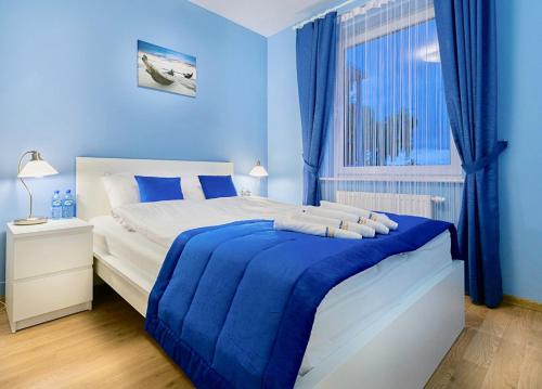 ダルウフコにあるApartament Komandorskiの青いベッドルーム(ベッド1台、窓付)