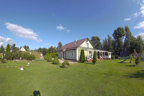 a small house in a field with a yard with a house at Rähni Guesthouse Lake Peipsi in Vilusi
