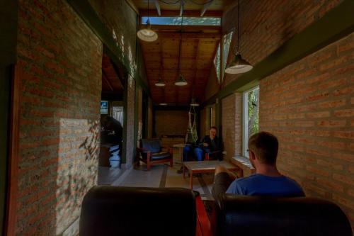 zwei Personen sitzen in Stühlen in einem Zimmer mit Ziegelwand in der Unterkunft Hostel Los Pioneros in El Calafate