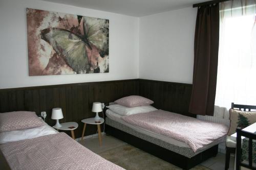 a bedroom with two beds and a butterfly painting on the wall at Fontana Vendégház in Tát