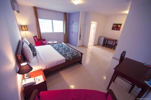 ein Hotelzimmer mit einem Bett, einem Tisch und einem Schreibtisch in der Unterkunft Hotel Adagio in Libreville