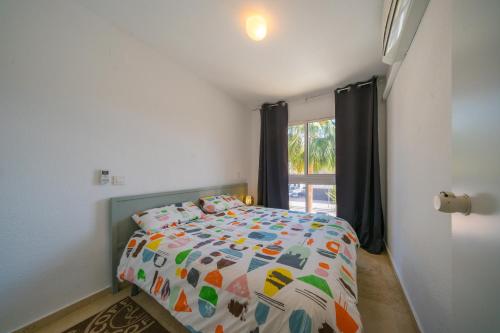 a bedroom with a bed with a colorful comforter and a window at Costa Blanca Albir 2 in Albir