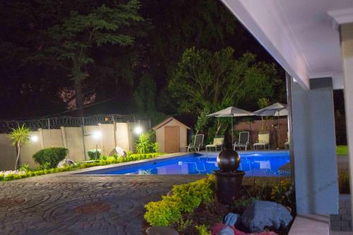 a swimming pool in a yard at night at Rekky Signature Guesthouse in Johannesburg