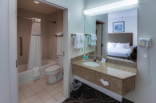 Ashmore Inn and Suites Lubbock في لوبوك: حمام مع حوض ومرحاض وسرير