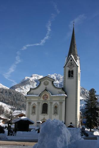 a church with a clock tower in the snow at Alpine Chalet Sauter in San Vigilio Di Marebbe