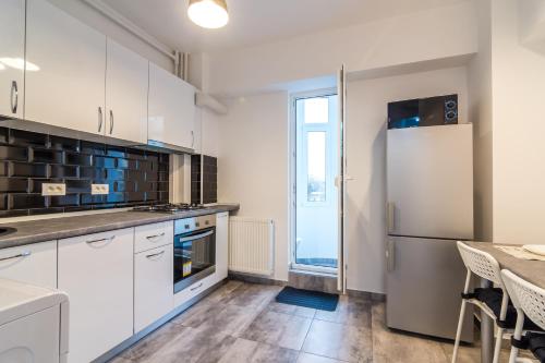 a kitchen with white cabinets and a refrigerator at Urban Retreat Near Metro & Mega Mall in Bucharest