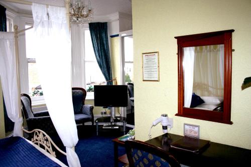 a living room with a bedroom with a mirror and a desk at Ilfracombe House Hotel - near Cliffs Pavilion in Southend-on-Sea