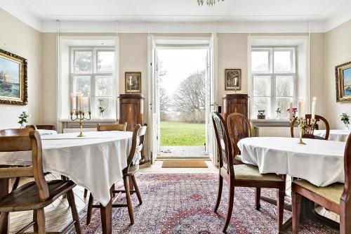 une salle à manger avec deux tables et une grande fenêtre dans l'établissement Ny Øbjerggaard Bed and Breakfast, à Lundby