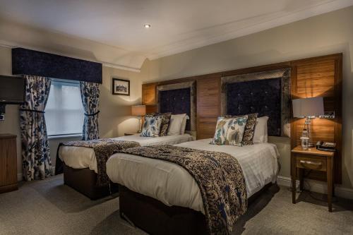 a hotel room with two beds and a window at The Admiral Rodney Hotel, Horncastle, Lincolnshire - The Coaching Inn Group in Horncastle